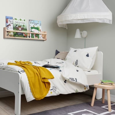Childrens bedroom with canopy bed, bookshelf, and stool.