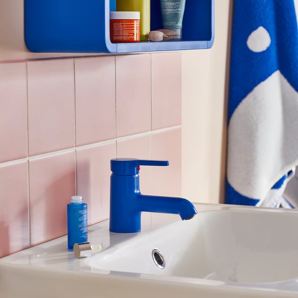 Blue BERGVATTNET mixer tap with ceramic cartridge fits neatly on white sink, contrasting pink tiles and blue shelf.
