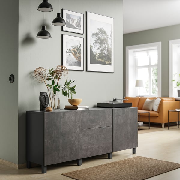 Modern living room with grey BESTÅ storage unit, featuring black pendant lights and orange seating area.
