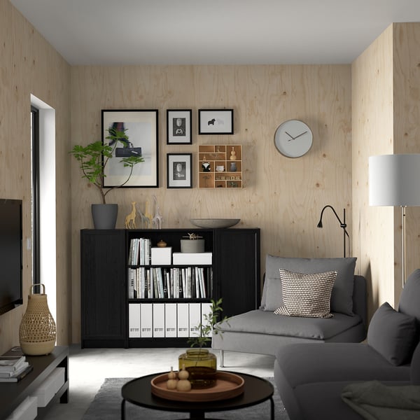 Minimalist living room with BILLY bookcase, grey sofa, wooden walls, and decorations.