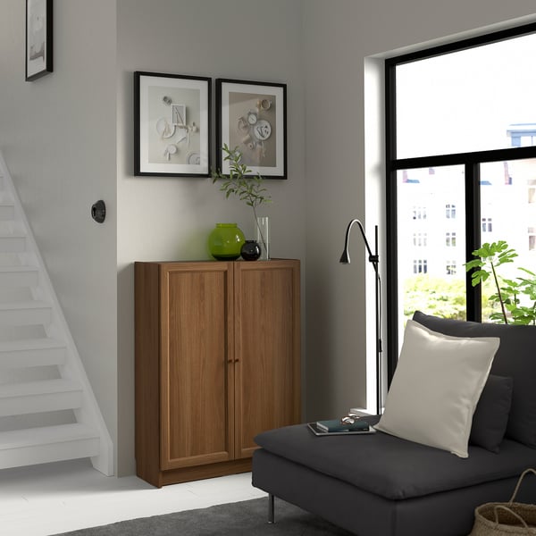 Modern living room with BILLY bookcase, green vase, plant, pictures, and grey sofa with light pillows.