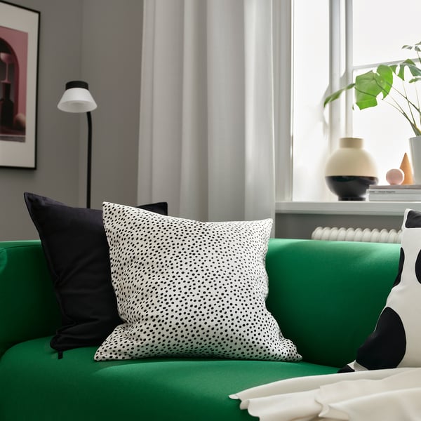 Green sofa, dotted pillow, white lamp, vases - living room.