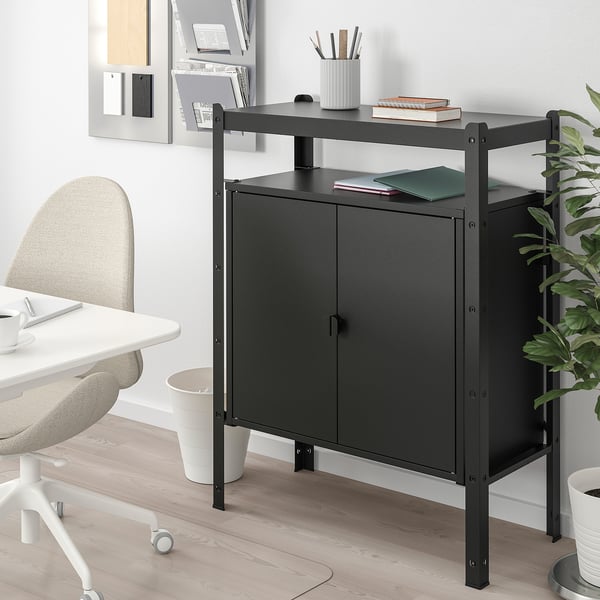 Black BROR storage cabinet with shelf, books, and pens next to white desk and chair, perfect for home office.