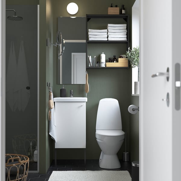 Modern bathroom: olive green walls, white fixtures, glass shower, mirrored cabinet, shelves with towels, white toilet.