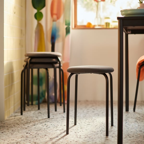 Four stackable stools, upholstered for comfort, in brightly lit room.