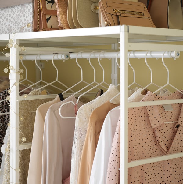 JONAXEL white clothes rack, holding pink and lace clothes, hanging neatly.