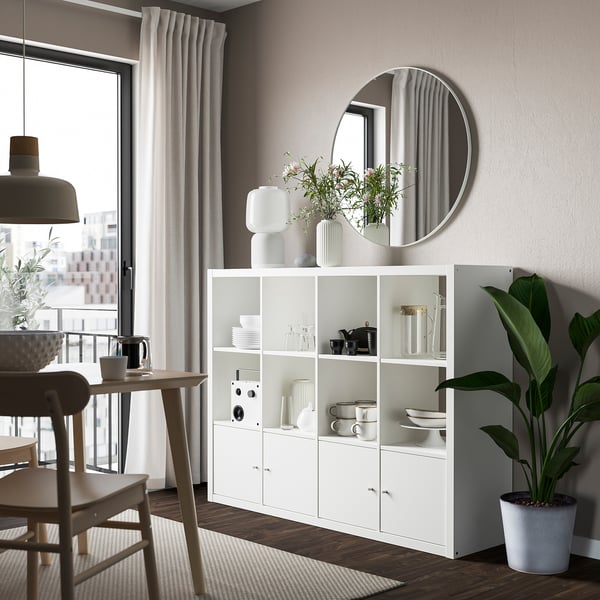 Modern kitchen with KALLAX shelf, dishes, plant, and mirror.