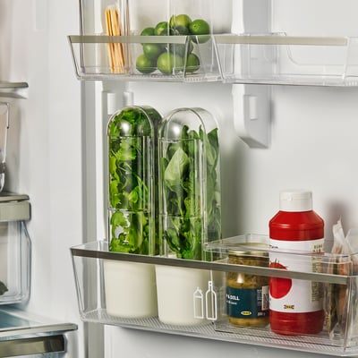 Fridge with clear containers holding herbs, limes, and condiments, keeping produce fresh.
