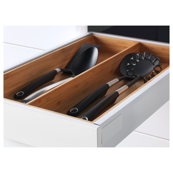 White kitchen drawer with wooden organizer, holding two black-handled kitchen utensils.