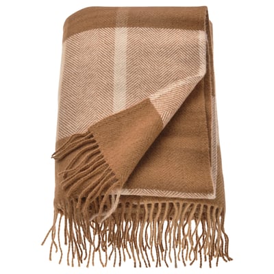 A folded MYRULL throw blanket, light brown with a herringbone pattern and fringe edges, made of 100% wool.