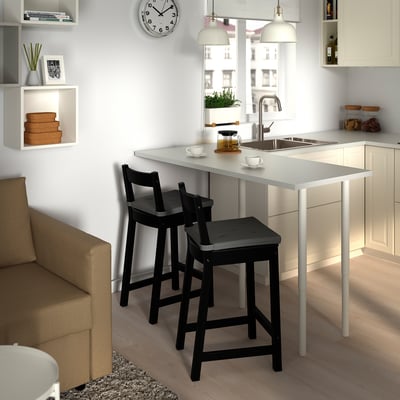 Modern kitchen with white counters, sink, large window, and NORDVIKEN stools. Shelves and clock complete the space.