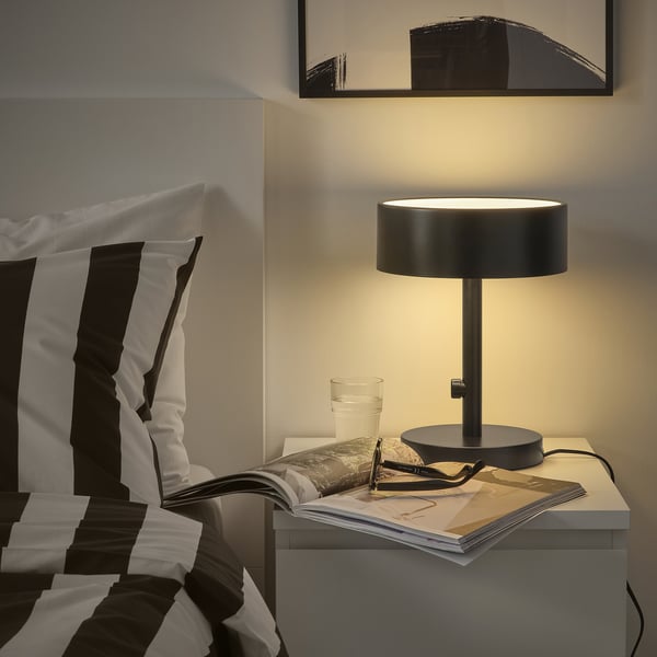 NYMÅNE lamp on bedside table, warm glow.