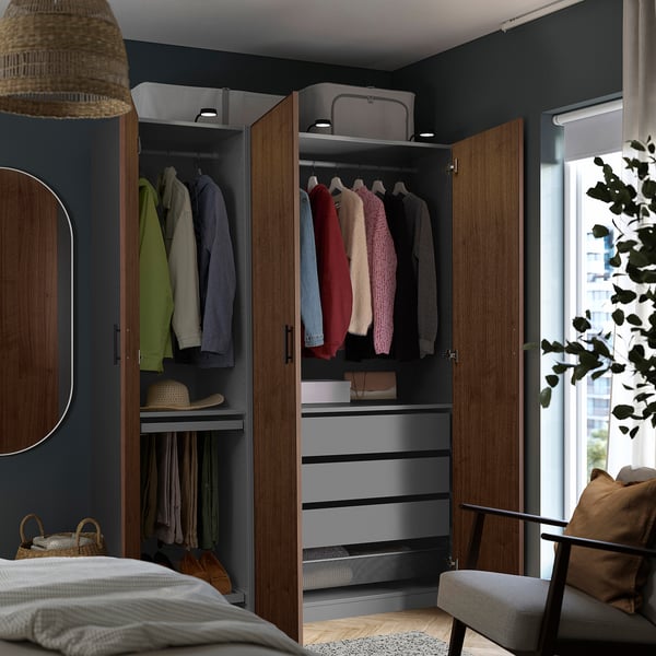 A modern bedroom with a walk-in closet featuring clothes, shelves, and drawers inside wooden wardrobes with dark walnut veneer.