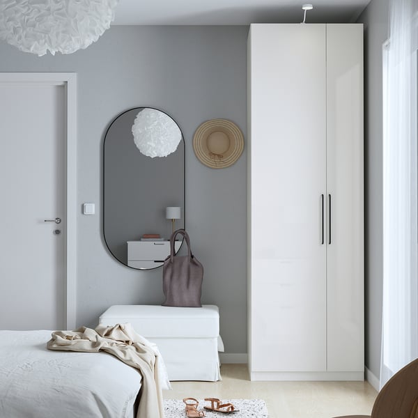 Minimalist bedroom with white PAX wardrobe, mirror, and dresser, lamp, light colours.