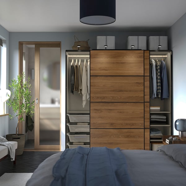 Bedroom with wooden closet, sliding doors, hanging clothes, and a bed with blue blanket.