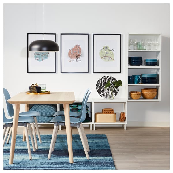 Modern dining room with wood table, blue decor, city maps & pendant light.
