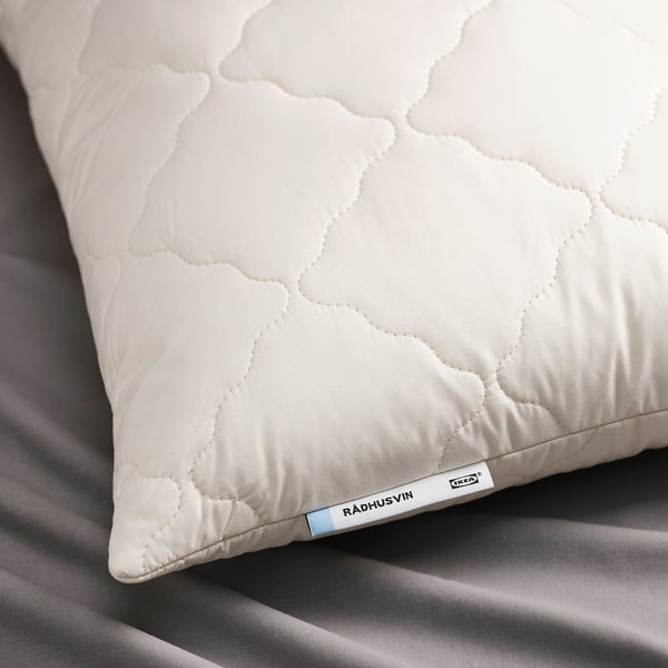 Close-up of a soft, white quilted pillow with RÅDHUSVIN tag, showcasing quality natural fibres.