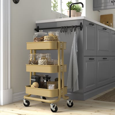 Yellow RÅSKOG storage cart with jars in modern kitchen, fits under counters.