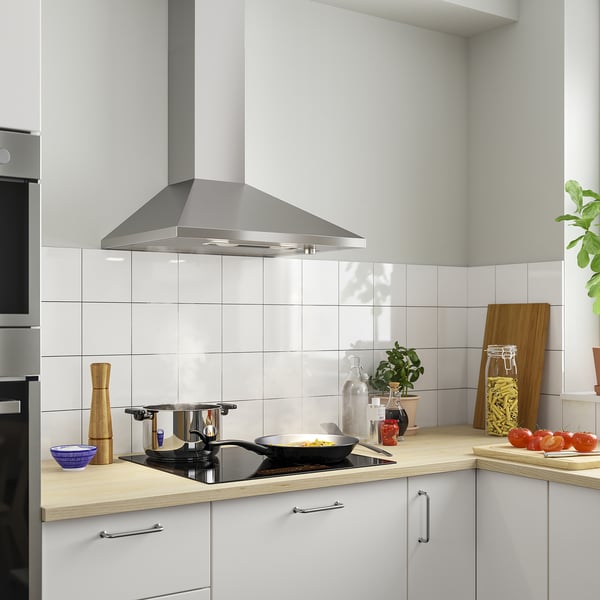 Modern kitchen with RYTMISK range hood, white cabinets, wood countertop, plants, jars.