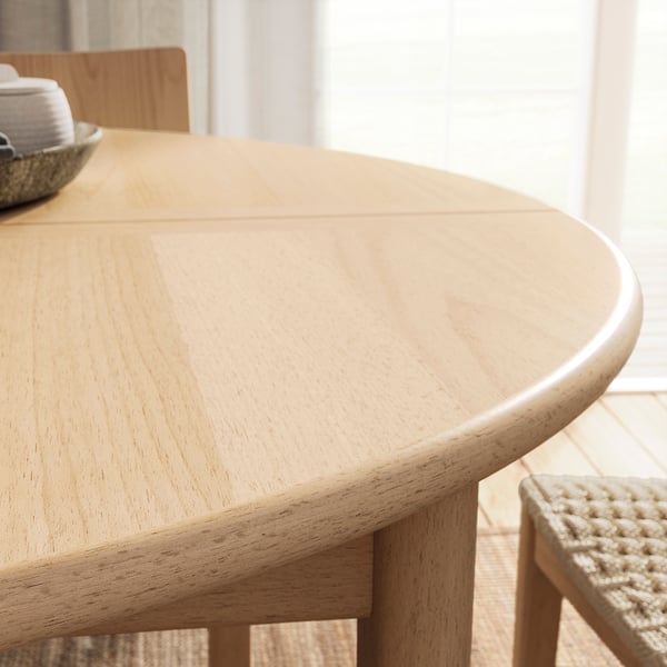 Round, light wood dining table with clean, smooth edges and butterfly leaf extension. Modern scandinavian design.