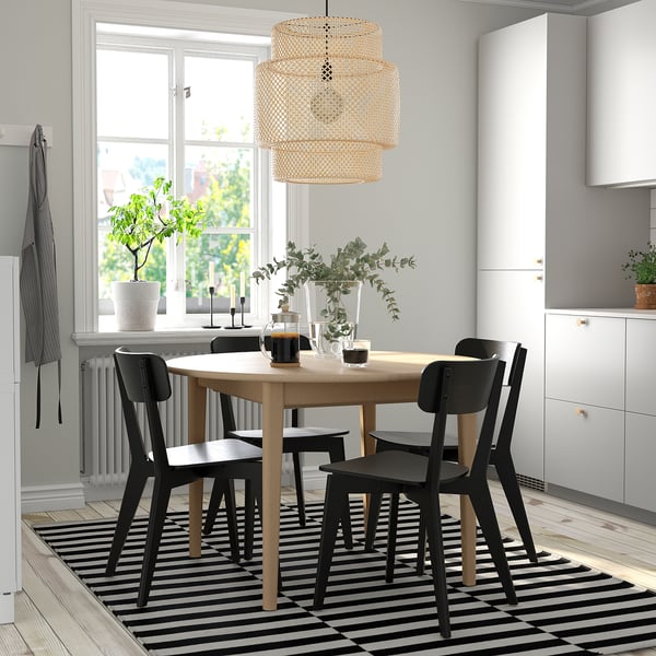 Modern 4-seat SKANSNÄS dining set with extendable table, curved chairs, striped rug, and pendant lamp. Bright room with window greenery and plants.