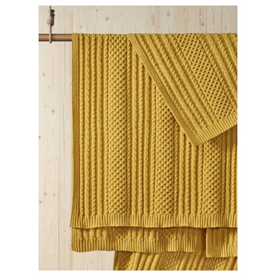 Mustard yellow SÖRBYSKOGEN throw displayed on wooden beam; textured knit pattern, draped neatly.
