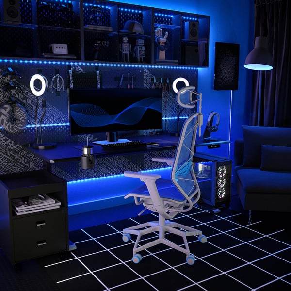 Modern gaming setup with white mesh STYRSPEL chair, blue led lights, dual monitors, and black decor.