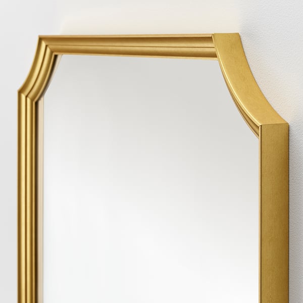 Gold framed mirror with elegant design, securely mounted on wall.