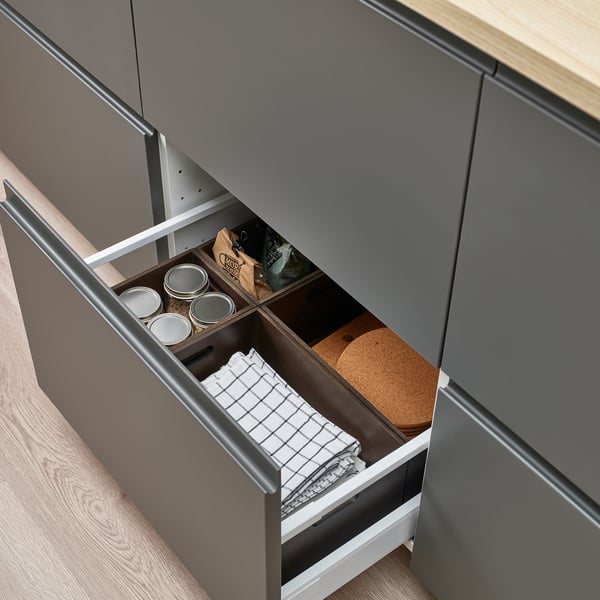 A drawer open to reveal storage boxes holding jars and a folded cloth.