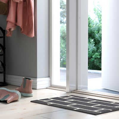 Grey & white geometric rug near doorway, polypropylene.