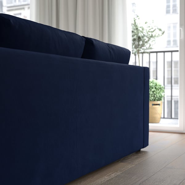Modern navy sofa near window, facing plant.