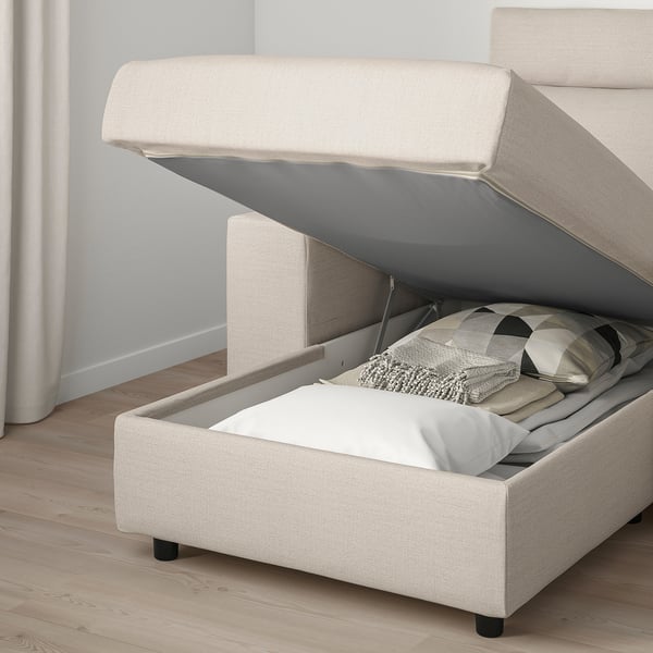 Beige sofa with storage. Lid open revealing pillows and blankets inside.