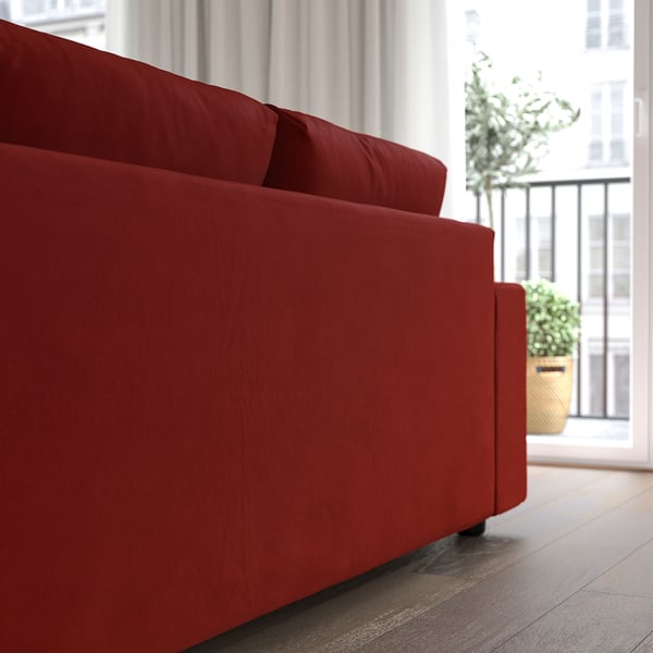 Red velvet sofa by window with cushions for comfort.