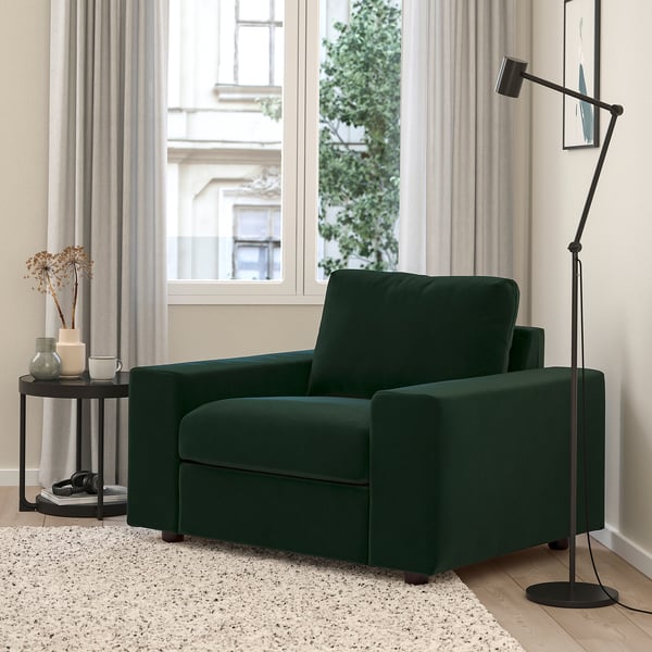 Cosy green VIMLE armchair near window, modern design, large side table with decor, stylish floor lamp.