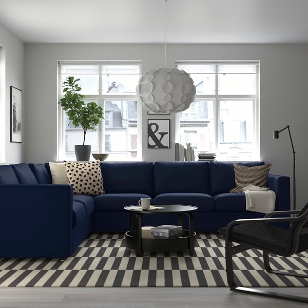 Modern living room with blue VIMLE sofa, throw pillows, coffee table, lamp, and large window.