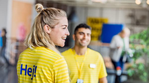 2 IKEA Mitarbeiter:innen in gelben Uniformen lachen gemeinsam.