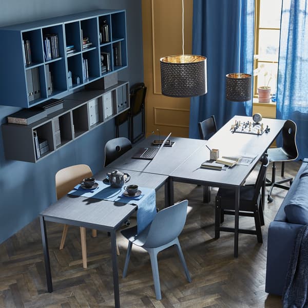 4 tables are arranged in a zigzag formation to accomodate different activities like chess, homework, and teatime.