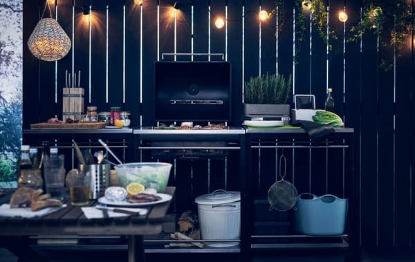 A barbeuqe and trolleys with various food and cooking utensils.
