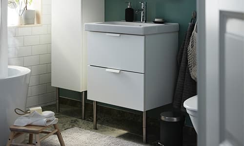 A bathroom cabinet and the side of a bathtub