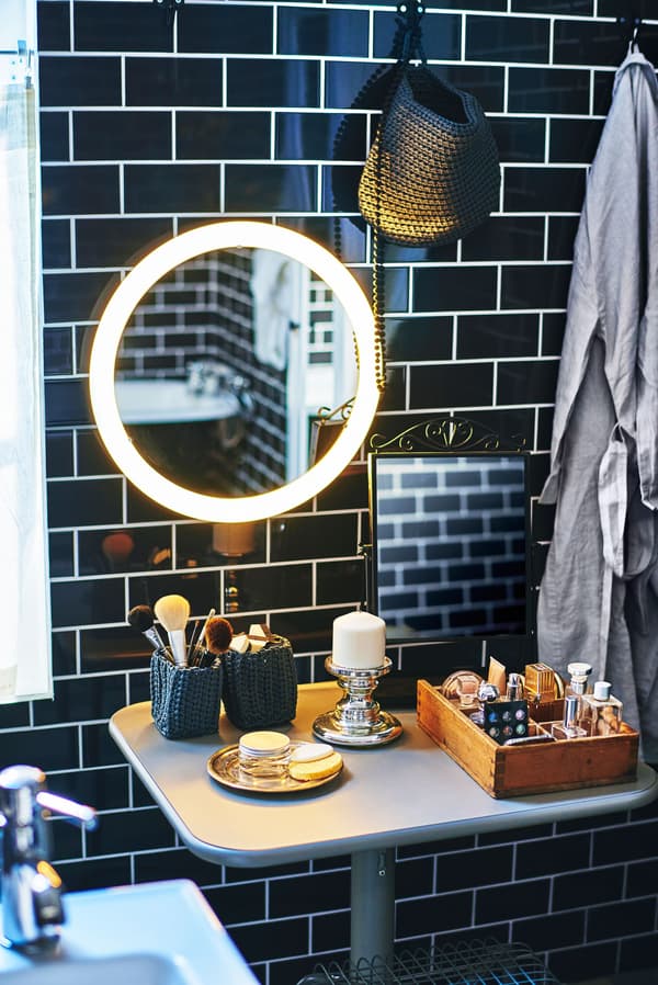 A bathroom makeup area under a lighted mirror.