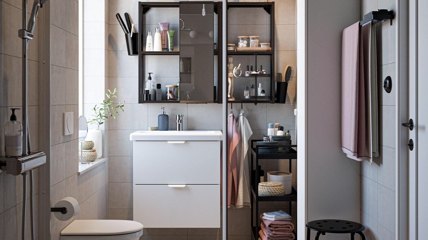 A bathroom with bathroom furniture in black/white, a chrome-plated shower set, light pink towels and a shower door in glass.