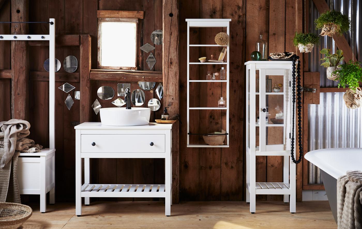 A bathroom with dark wooden walls and traditional-style white storage furniture.