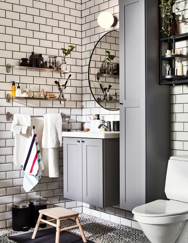 A bathroom with grey ENHET bathroom furniture and wall mounted BROGRUND glass shelves, one for him and one for her.