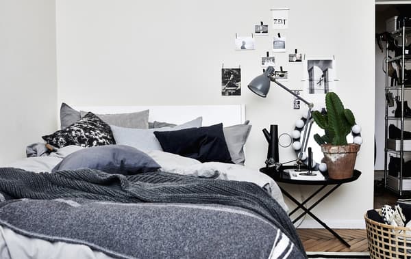 A bed covered in layers of throws and cushions.