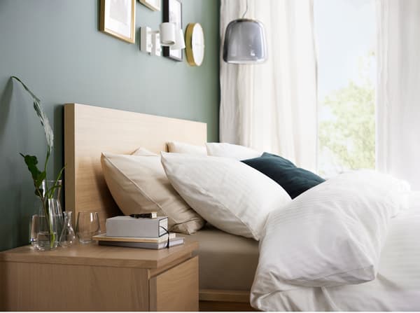 A bed frame and bedside table in white stained oak veneer and a quilt cover, pillowcases and curtains in white.