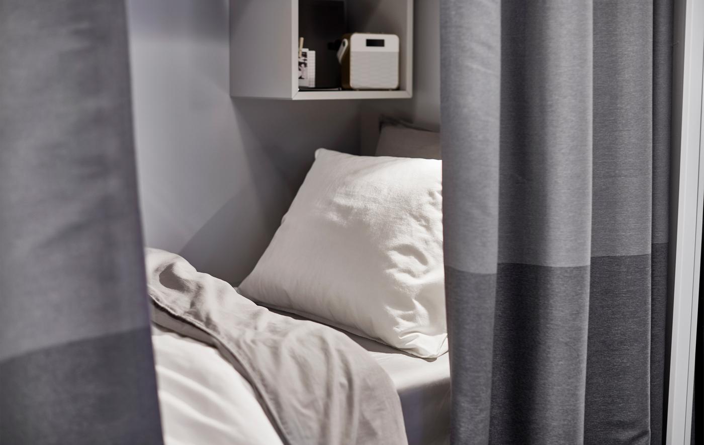 A bed is shown behind a curtain room divider.