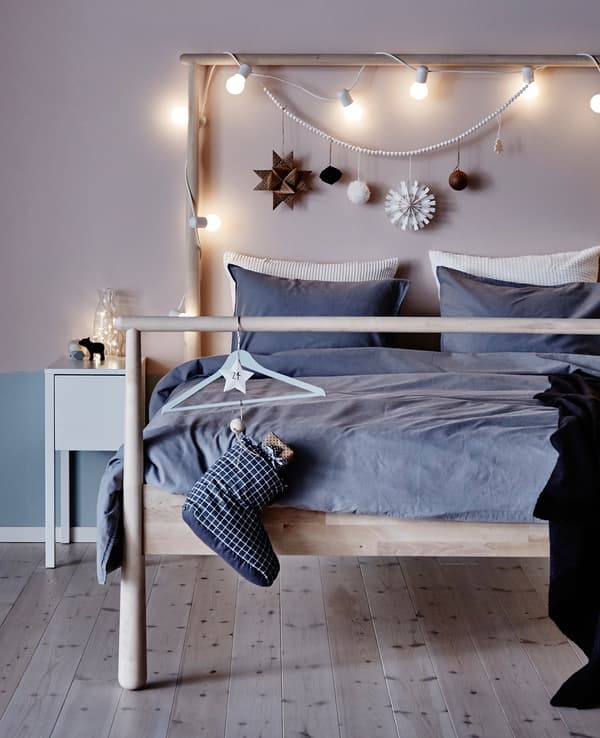 A bed is simply decorated with a string of lights and some ornaments.