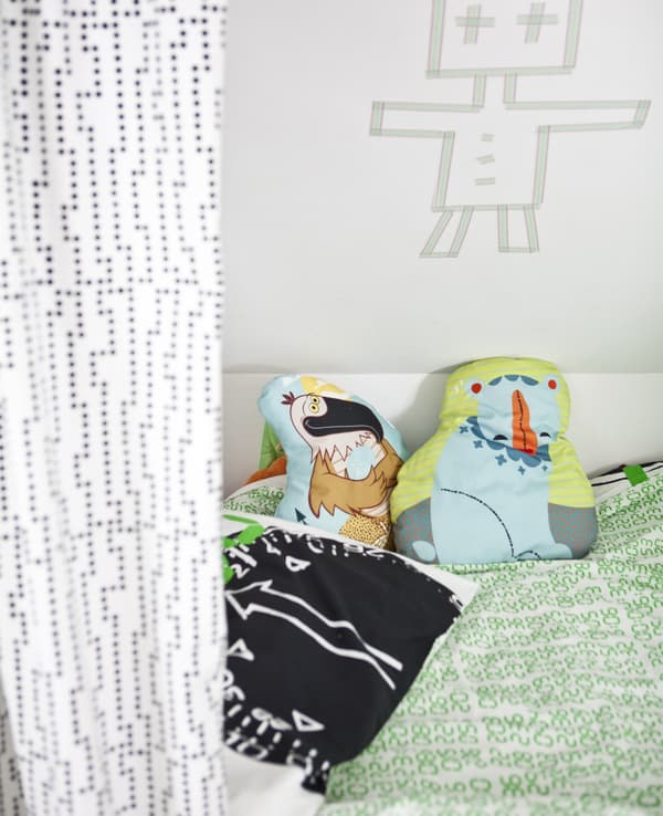 A bed with colourful bedding and cushions.