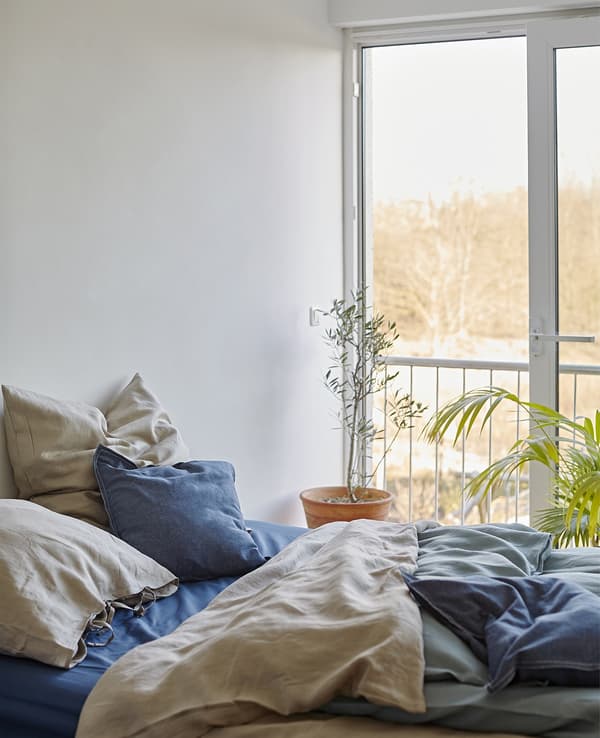 A bed with layered bedding in natural colours.