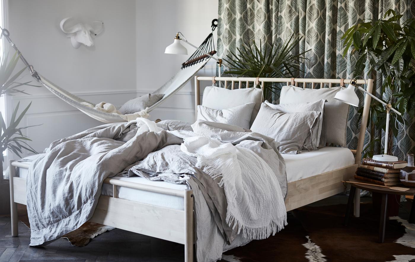 A bedroom with a BJÖRKSNÄS bed frame, RANARP lamp and STOCKHOLM coffee table.
